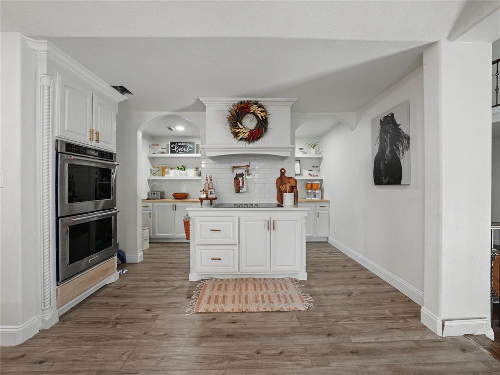 6701 Nauert Road Forest Hill, TX 76140 - Photo 12 of 40 Kitchen featuring a central island, white cabinetry, wood-finish flooring, stainless steel double wall ovens, and open shelving