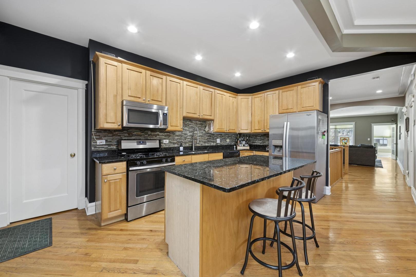 6743 North Sheridan Road, Unit 1N Chicago, IL 60626 - Photo 14 of 26 a kitchen with stainless steel appliances granite countertop a refrigerator a stove top oven a sink dishwasher and white cabinets with wooden floor