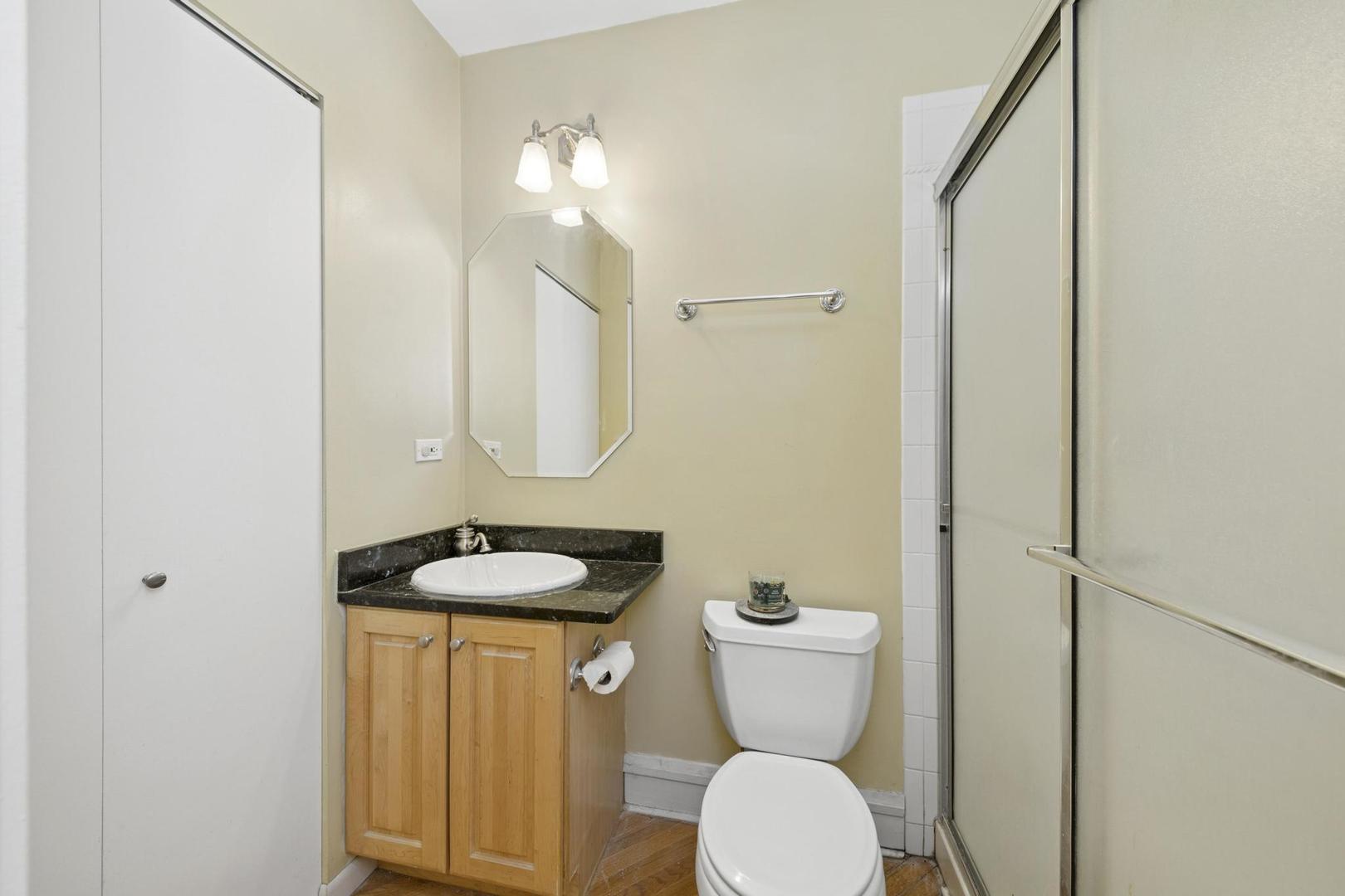 6743 North Sheridan Road, Unit 1N Chicago, IL 60626 - Photo 19 of 26 a bathroom with a granite countertop toilet sink and mirror