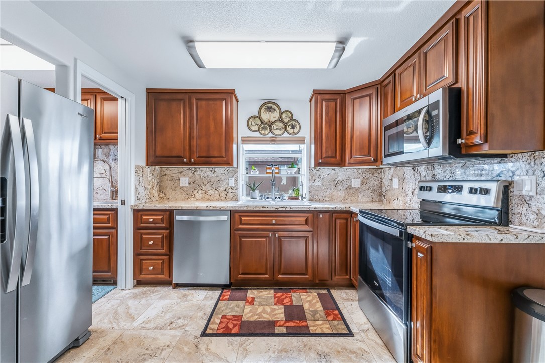 2000 Ramar Road, Unit 126 Bullhead City, AZ 86442 - Photo 12 of 65 Kitchen with appliances with stainless steel finishes, light stone counters, brown cabinetry, and decorative backsplash