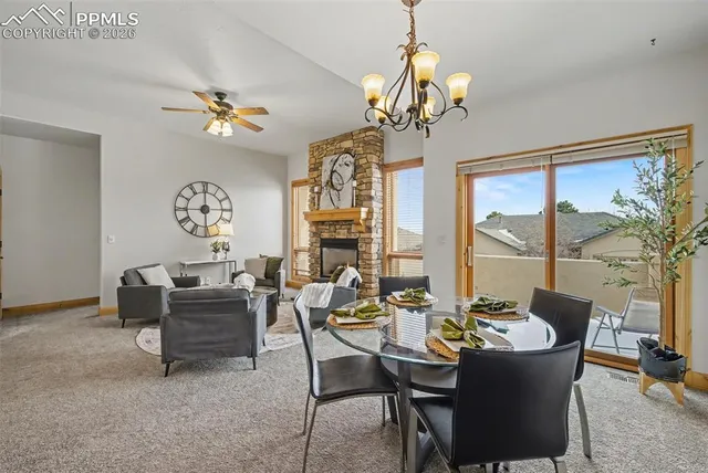 a view of a dining room with furniture a chandelier and large windows