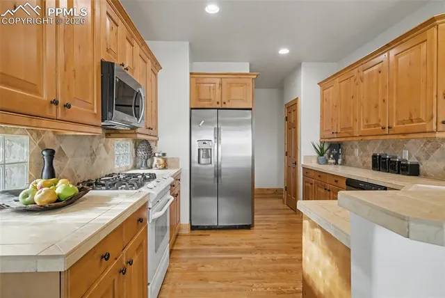 a kitchen with stainless steel appliances granite countertop a sink a stove and a refrigerator
