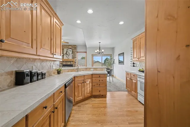 a kitchen with stainless steel appliances granite countertop a refrigerator a sink dishwasher and a stove with wooden cabinets