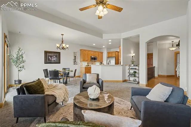 a living room with furniture kitchen view and a chandelier