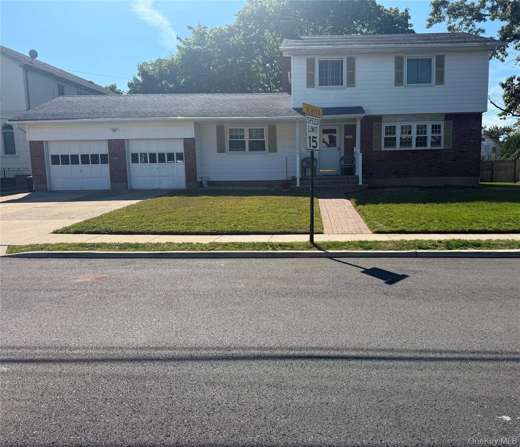 View of front facade with a front yard, brick siding, an attached garage, and concrete driveway