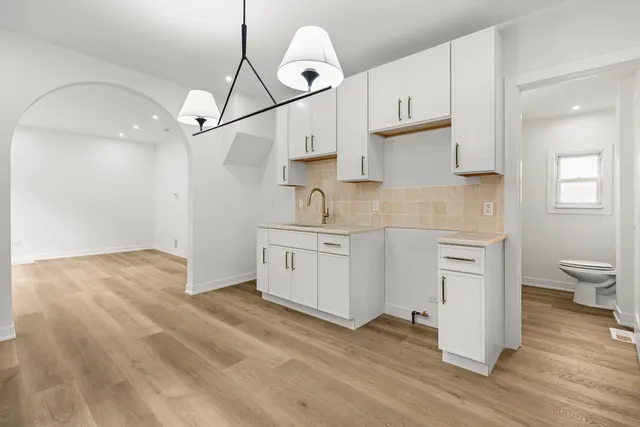 a kitchen with white cabinets stainless steel appliances and wooden floor