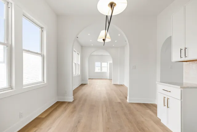 a view of a room with wooden floor chandelier and windows