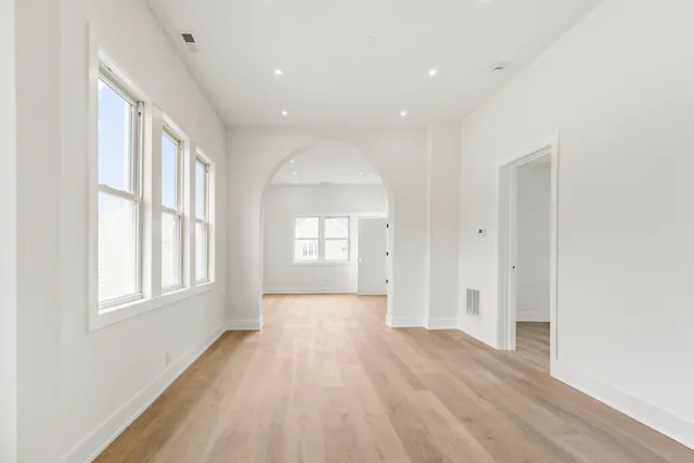 an empty room with wooden floor and windows