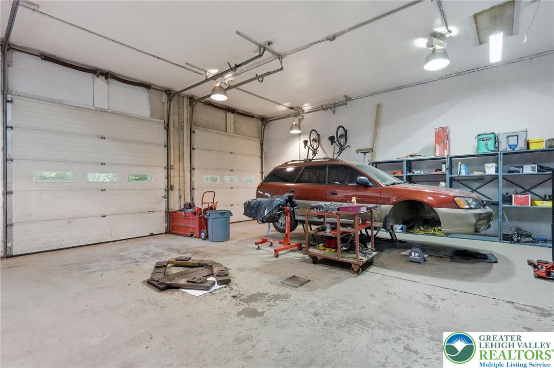 9033 Loop Road Slatington, PA 18080 - Photo 32 of 53 A spacious, well-lit garage with multiple overhead doors and ample storage, ideal for vehicles or a workshop.