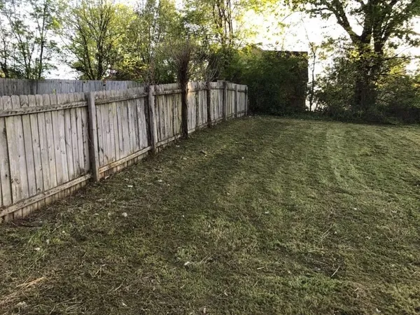 a view of backyard with wooden fence and trees