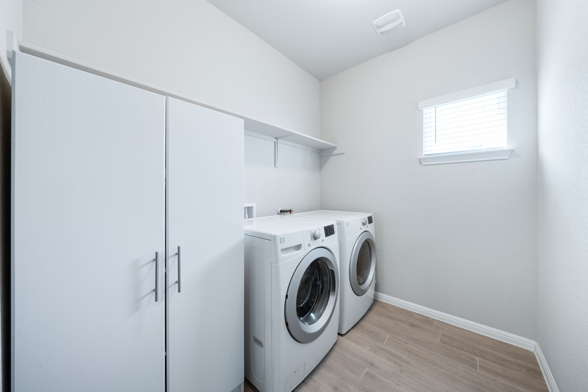 2412 Starhill Ranch Street Georgetown, TX 78628 - Photo 30 of 40 A well-lit laundry room offers ample storage and modern washer/dryer units.