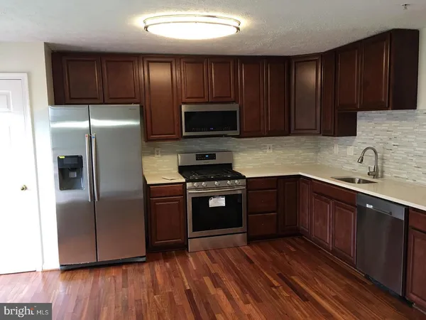 a kitchen with wooden floors stainless steel appliances and cabinets