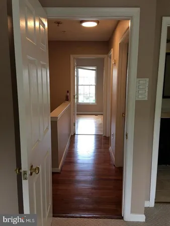 a hallway with wooden floor chandelier and livingroom view