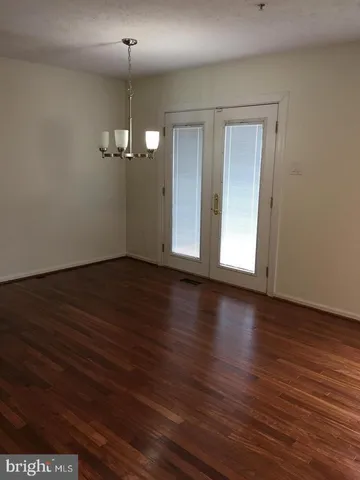an empty room with wooden floor chandelier and windows