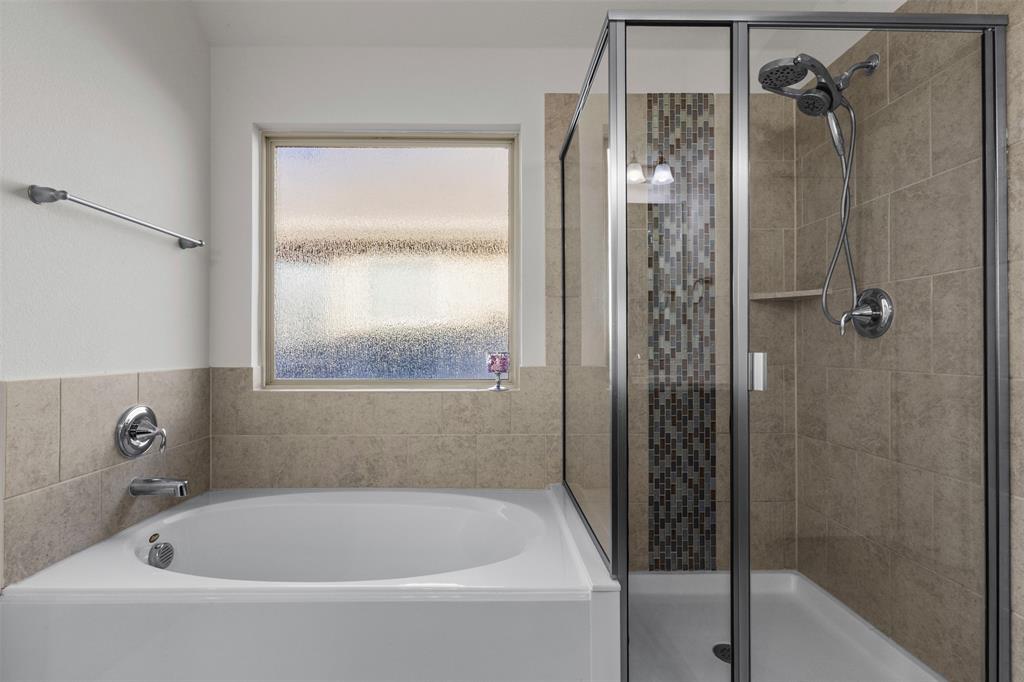 1740 Rio Costilla Road Fort Worth, TX 76131 - Photo 27 of 40 Soaking tub with chrome fixtures, tiled shower with glass enclosure, built-in shower niche, and mosaic tile accent