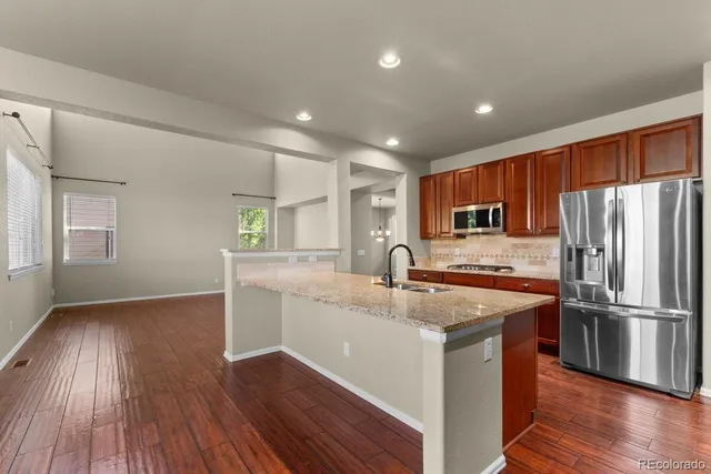 a kitchen with stainless steel appliances granite countertop a refrigerator a sink dishwasher a stove with wooden floors