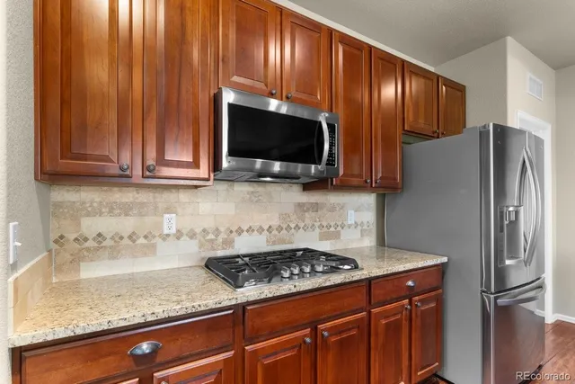 a kitchen with granite countertop stainless steel appliances and wooden cabinets