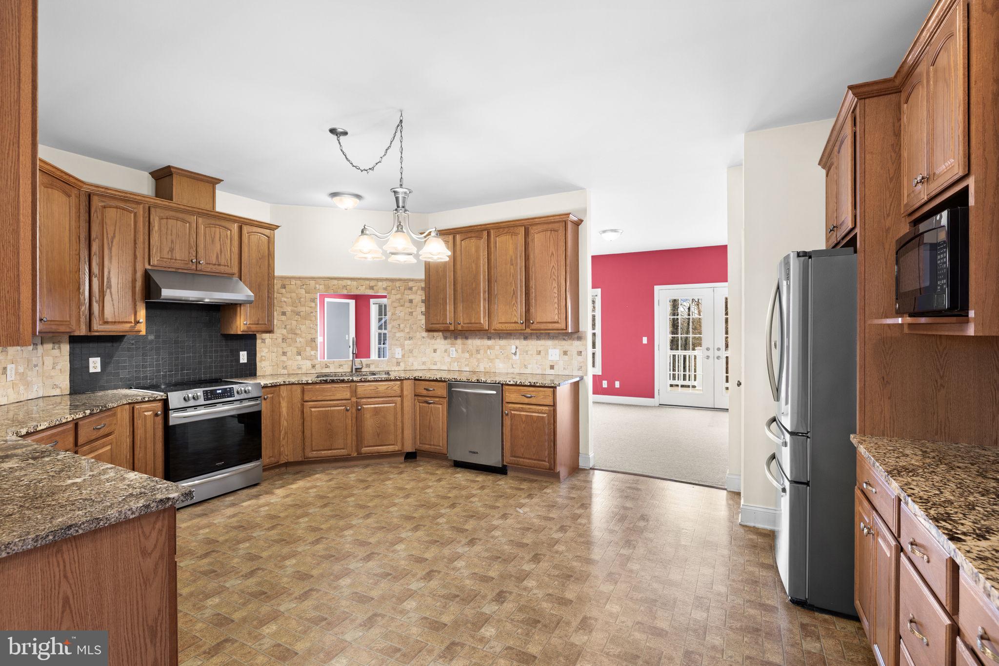 2481 Yanceyville Road Louisa, VA 23093 - Photo 19 of 66 a kitchen with stainless steel appliances granite countertop a stove top oven a sink a counter space and cabinets