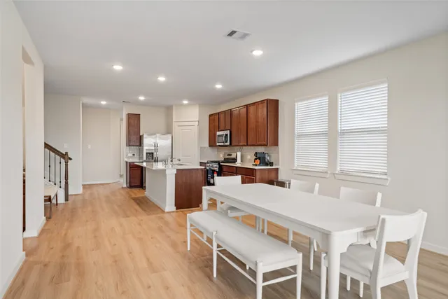 a living room with stainless steel appliances kitchen island granite countertop a kitchen island a sink a stove a dining table and chairs