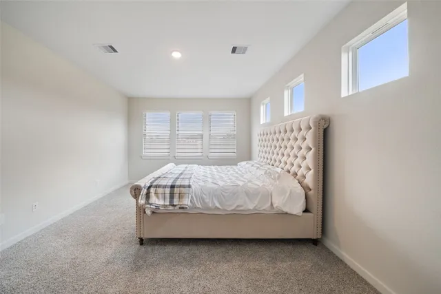 a bed sitting in a spacious bedroom next to a window
