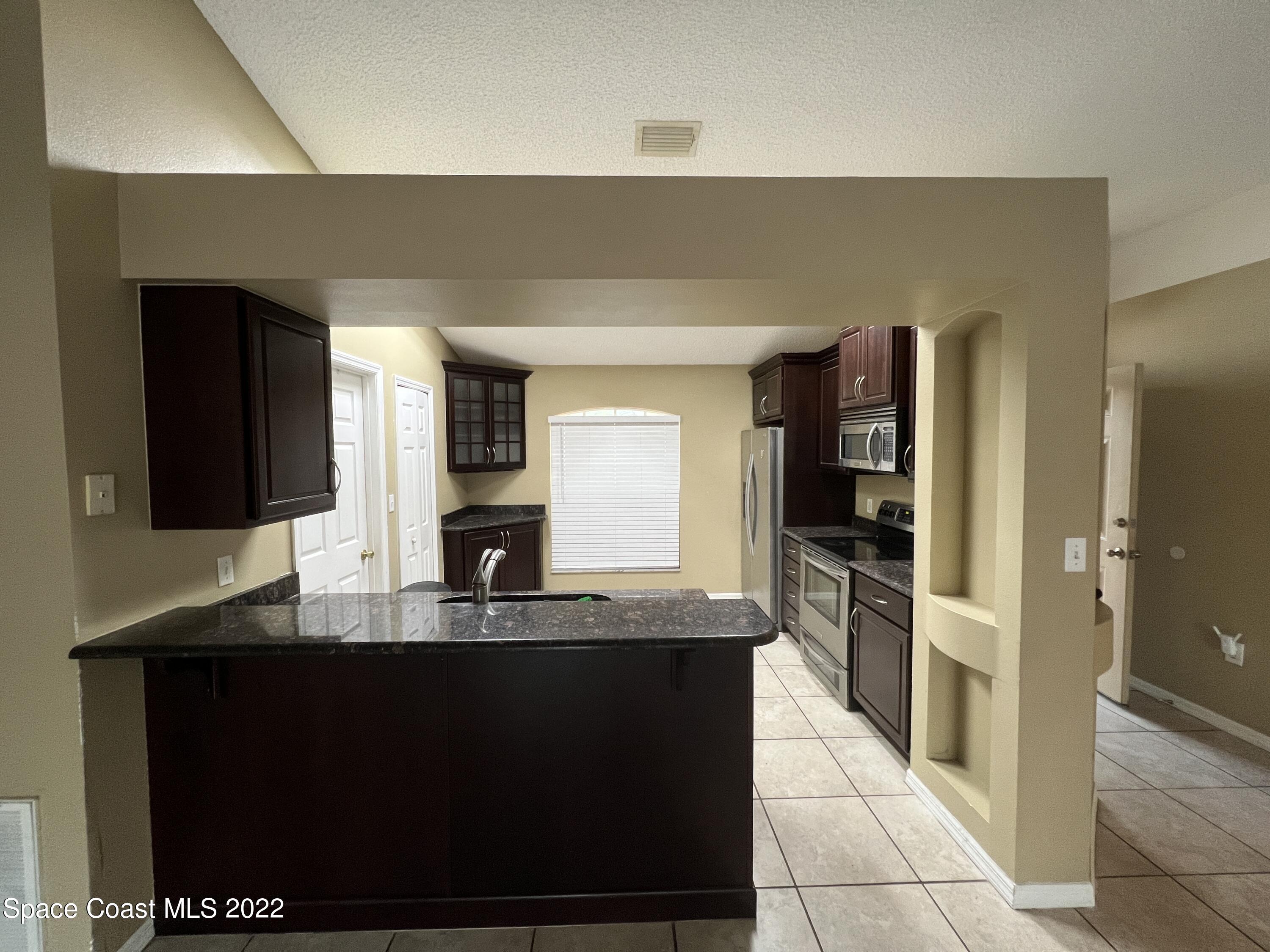 1873 Cleveland Street Northeast Palm Bay, FL 32905 - Photo 12 of 28 a kitchen with kitchen island granite countertop a refrigerator and a sink
