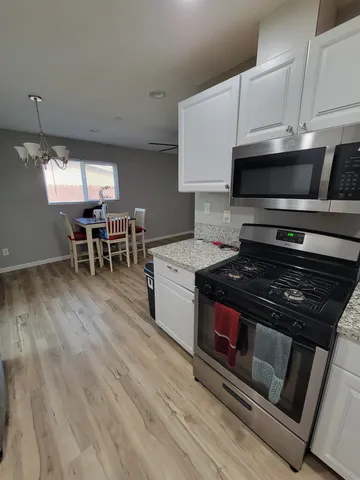 a kitchen with granite countertop white cabinets and stainless steel appliances