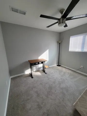 a view of a livingroom with workspace and a ceiling fan