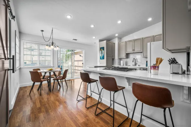 a kitchen with stainless steel appliances granite countertop table chairs stove and wooden floor