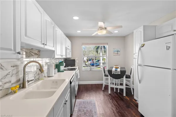 a kitchen with a refrigerator a sink dishwasher a dining table and chairs with wooden floor