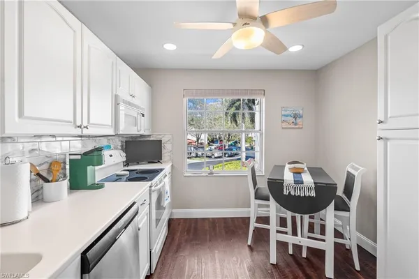 a kitchen with stainless steel appliances a dining table chairs and a refrigerator