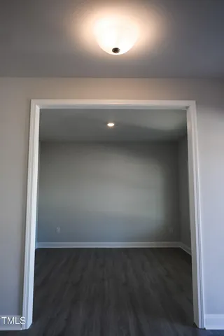 an empty room with wooden floor fireplace and windows