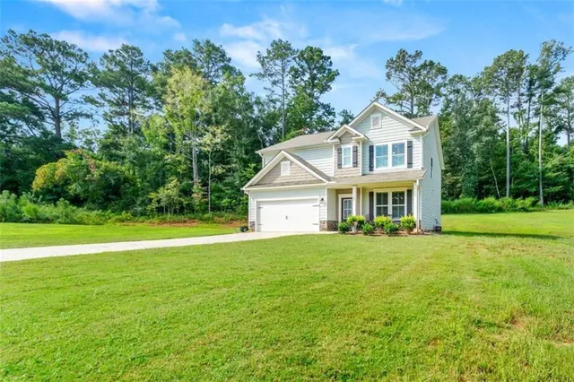 a view of a house with a big yard and large trees