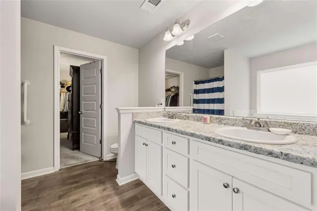 a bathroom with a granite countertop double vanity sink and a mirror