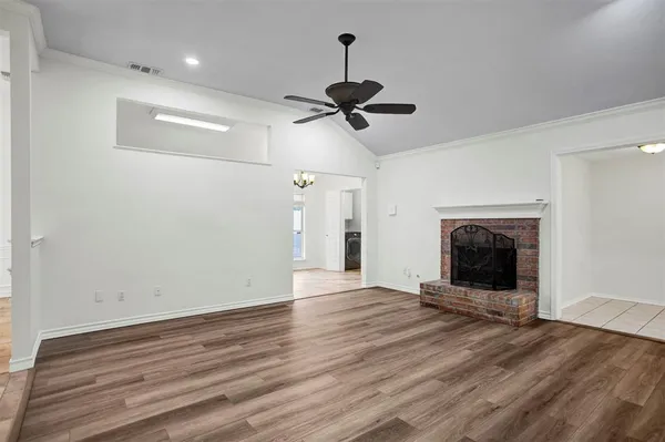 a view of an empty room with wooden floor fireplace and a window
