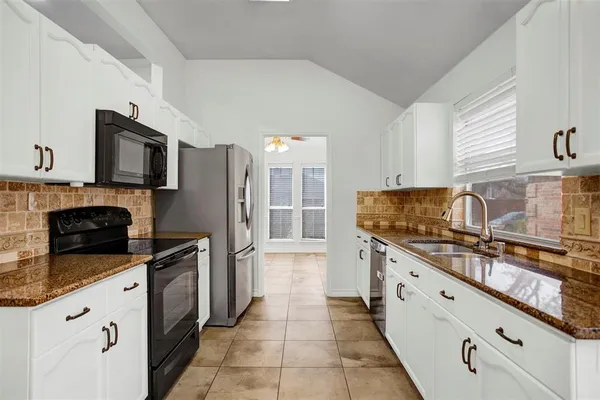 a kitchen with stainless steel appliances granite countertop a sink stove refrigerator and cabinets