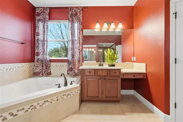 a bathroom with a tub a sink and mirror