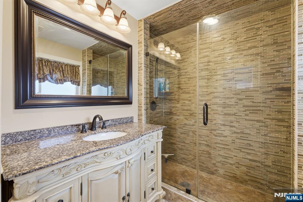 385 Berkeley Avenue Bloomfield, NJ 07003 - Photo 13 of 39 a bathroom with a granite countertop sink a mirror and a shower