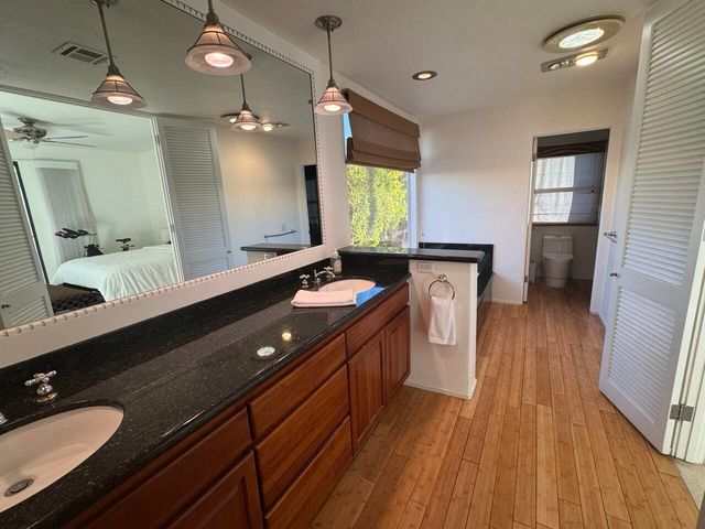 a spacious bathroom with a granite countertop sink toilet a mirror and shower