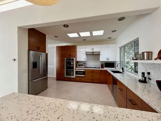 a kitchen with stainless steel appliances kitchen island granite countertop a refrigerator and a sink