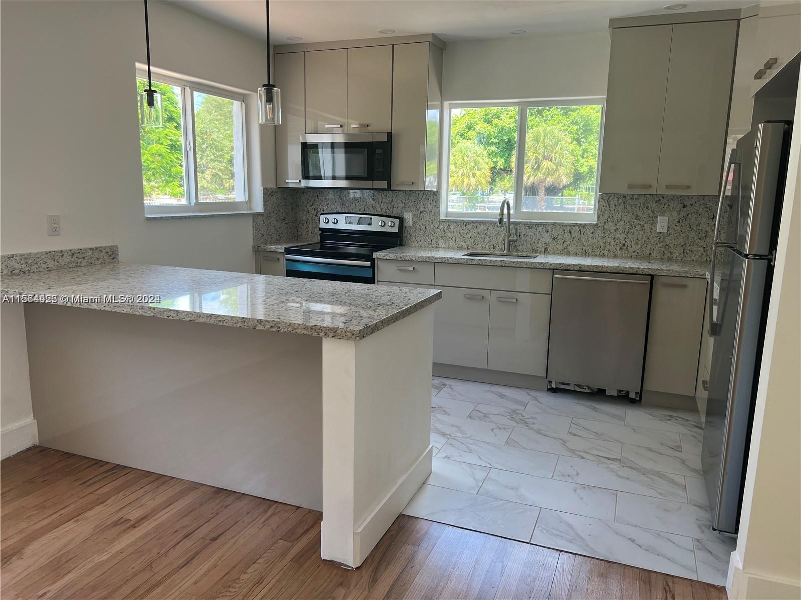 245 Southwest 24th Road, Unit 1 Miami, FL 33129 - Photo 2 of 14 a kitchen with kitchen island granite countertop a sink window and cabinets