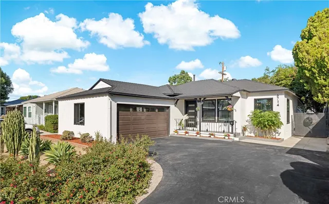 a front view of a house with a yard and potted plants