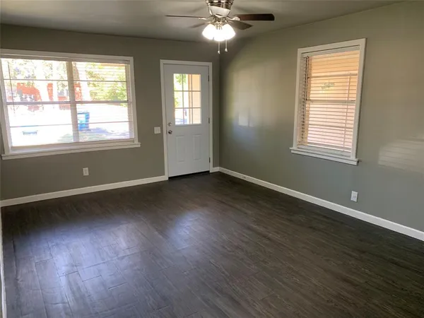 a view of an empty room with wooden floor and a window
