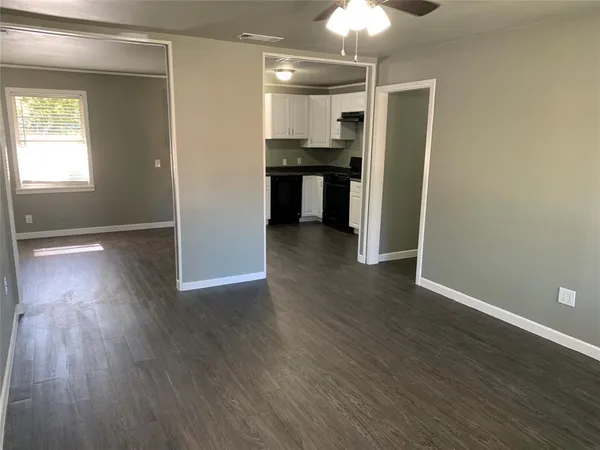 an empty room with wooden floor closet and windows