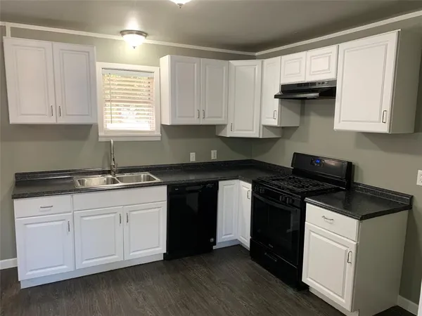 a kitchen with granite countertop white cabinets and a stove with wooden floor