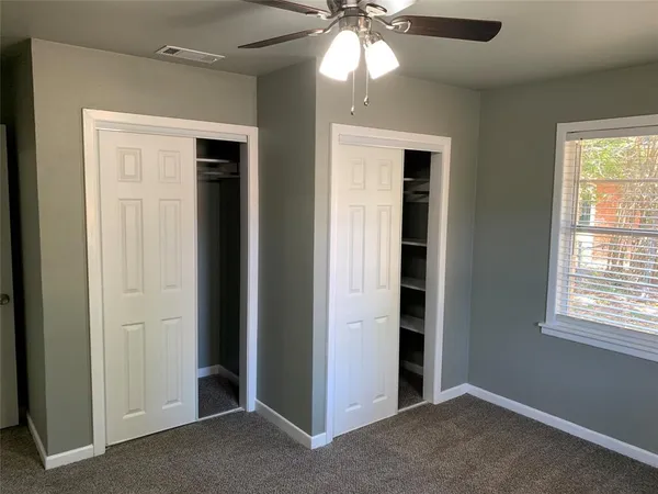 an empty room with closet and a chandelier fan