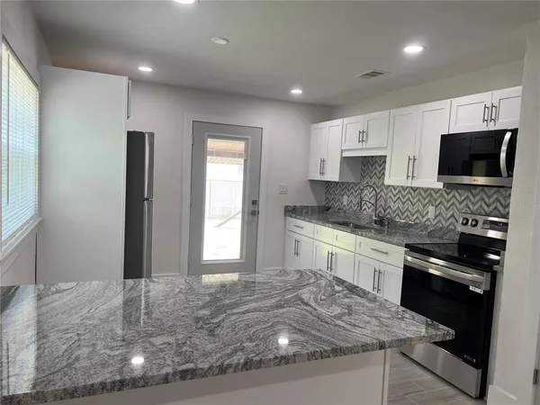 a kitchen with kitchen island granite countertop a stove sink and microwave