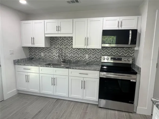 a kitchen with granite countertop white cabinets and stainless steel appliances