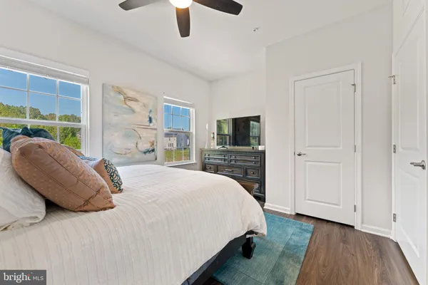 a spacious bedroom with a bed a couch and large window with wooden floor