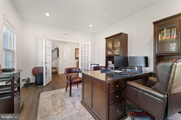 a kitchen with stainless steel appliances kitchen island granite countertop a stove top oven a sink dishwasher a refrigerator and a dining table with wooden floor