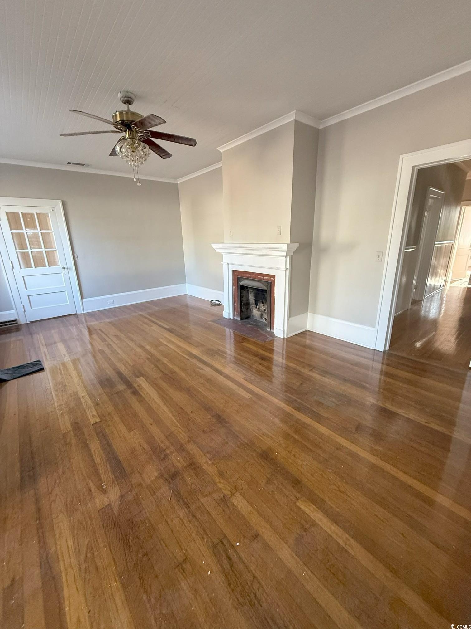 305 East Bamberg Street Latta, SC 29565 - Photo 13 of 13 Unfurnished living room with crown molding, dark wood-style floors, a brick fireplace, and ceiling fan